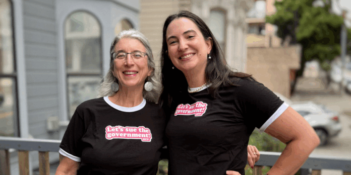 Guía de Regalos de Vacaciones de EFF: Sugerencias para Entusiastas Two people outside wearing black t-shirts with white trim that say "Let's sue the Government!"