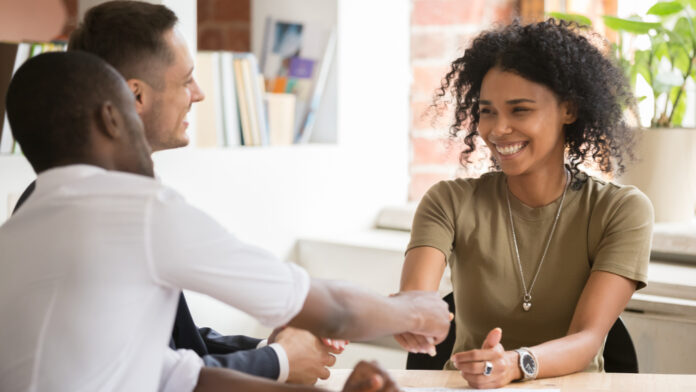 Incremento en la Tasa de Empleo y Reducción del Desempleo A young women shaking hands with a person sitting across the table.