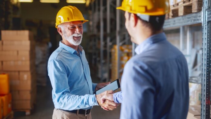 La duración de la vida laboral alcanza los 37.5 años two men wearing yellow helmets and hand shaking