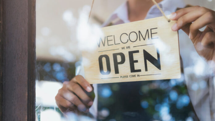El Auge Empresarial: 3.5 Millones de Nuevos Negocios Abiertos en A person hanging a sighn that reads: open.